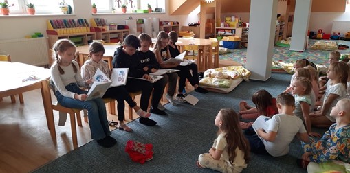 Páťáci čtou dětem ve školce.